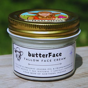 May include: A small jar of butterFace Tallow Face Cream with a gold lid and a white label. The label includes the text "butterFace Tallow Face Cream" and additional text about the ingredients and maker, "Chad Mom of Northern Indiana."