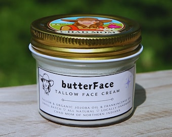 May include: A small jar of butterFace Tallow Face Cream with a gold lid and a white label. The label includes the text "butterFace Tallow Face Cream" and additional text about the ingredients and maker, "Chad Mom of Northern Indiana."