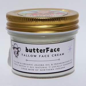May include: A small glass jar of "butterFace" tallow face cream with a gold lid. The label includes the product name, ingredients, and the phrase "Chad Mom of Northern Indiana". The jar is filled with a white cream.
