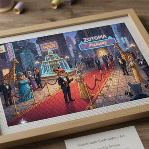 Puede incluir: Imagen de un bordado enmarcado que representa una escena de Zootopia. La obra muestra personajes en una alfombra roja en un estreno, con el título "Zootopia Premiere". El marco es de color marrón claro y la escena es detallada.