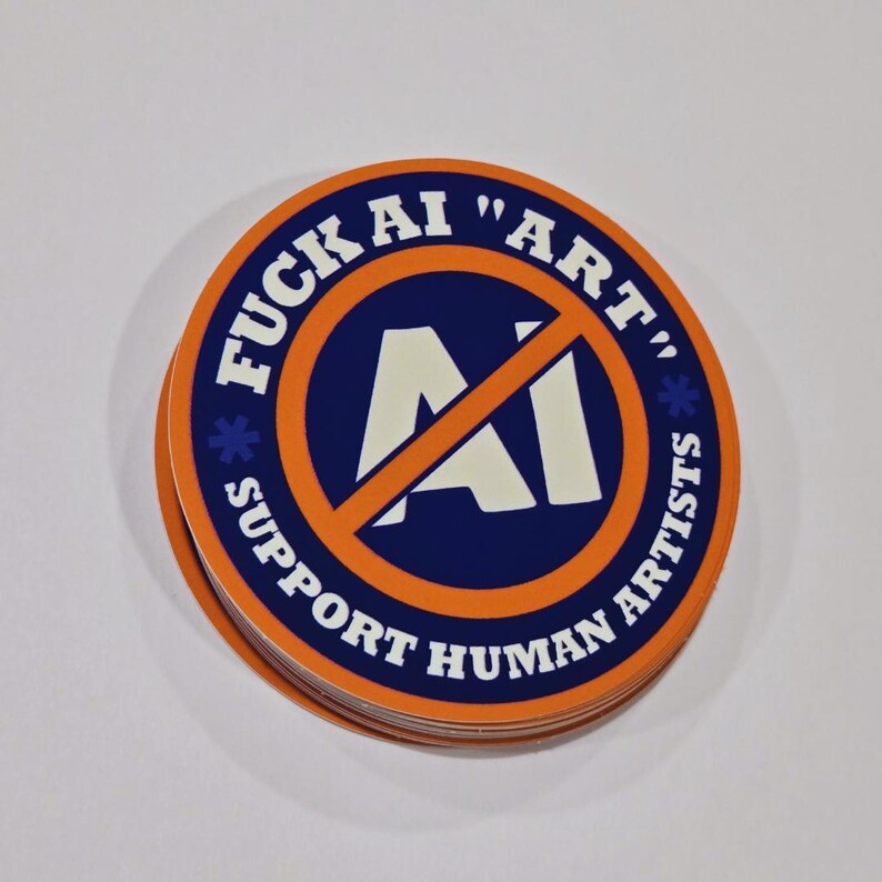 May include: A stack of round stickers with a blue and orange design. The stickers have the text "FUCK AI 'ART' SUPPORT HUMAN ARTISTS" in white. The center of the sticker has a white "AI" symbol crossed out with an orange line.