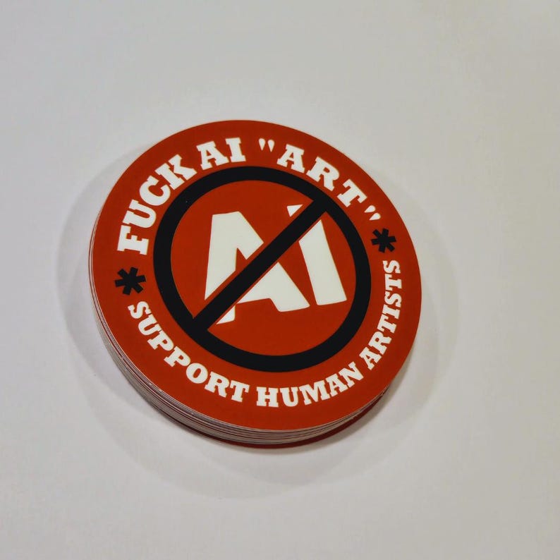 May include: A stack of round red stickers with white text and a black border. The text reads "FUCK AI 'ART'" and "SUPPORT HUMAN ARTISTS". The center features a white "AI" symbol crossed out with a black line.