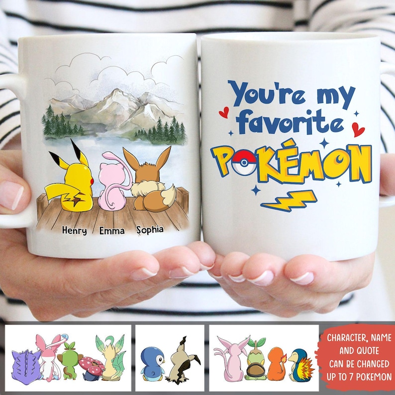 May include: White ceramic mug featuring a scenic illustration of Pikachu, Mew, and Eevee on a dock, with mountains and water in the background. The other side says "You're my favorite Pok&eacute;mon".