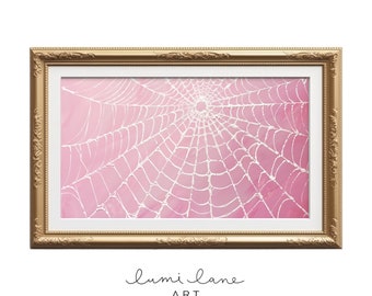 May include: A framed pink and white watercolor painting of a spider web. The web is in the center of the canvas and is surrounded by a pink background. The frame is gold and has a decorative design.