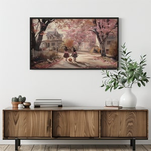 May include: Two children dressed as witches walk down a street lined with trees in autumn. They are carrying a pumpkin and wearing black hats. The street is covered in fallen leaves.