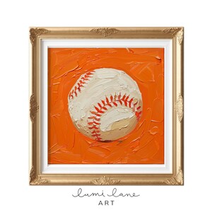 May include: A white baseball with red stitching is painted on a bright orange background. The painting is framed in a gold frame.