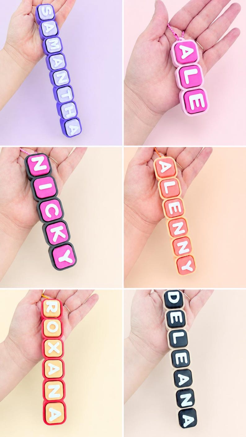 Op de afbeelding: Een collectie van zes gepersonaliseerde sleutelhangers met vierkante, kleurrijke siliconen kralen met witte reli&euml;fletters. Elke sleutelhanger toont een unieke naam: SAMANTHA, ALE, NICKY, ALENNY, ROXANA en DELEANA, bevestigd aan een kleine ketting.