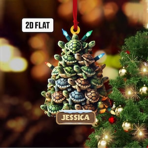 May include: A Christmas ornament shaped like a Christmas tree made of stacked turtles. The ornament is decorated with small, colorful lights and a wooden sign that reads "Jessica".
