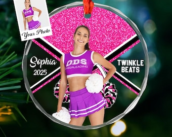 May include: A personalized, round Christmas ornament featuring a cheerleader in a purple and white uniform. The ornament includes the text "Sophia 2025" and "Twinkle Beats", with a photo insert that says "Your Photo".