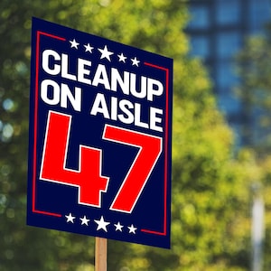 K&ouml;nnte beinhalten: Ein rechteckiges Schild mit dem Text "CLEANUP ON AISLE 47" in wei&szlig;en Buchstaben auf blauem Grund. Die Zahl 47 ist rot. Das Schild hat einen roten Rand und wei&szlig;e Sterne oben und unten.