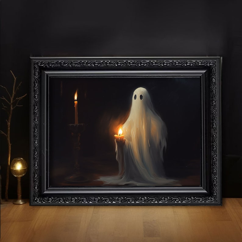 May include: A framed rectangular wall art piece featuring a white ghost figure draped in a sheet, holding a lit candle. The ghost stands next to a tall candlestick with another lit candle against a dark background, all encased in a black ornate frame.