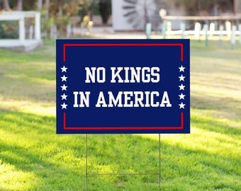 Op de afbeelding: Een blauw en rood tuinschild met witte tekst die "NO KINGS IN AMERICA" luidt. Het bord heeft een rode rand en witte sterren aan de zijkanten.