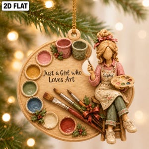 May include: A decorative ornament shaped like a wooden paint palette featuring the text Just a Girl who Loves Art. It includes eight paint wells, two paintbrushes, and a sculpted figure wearing an apron with the name Sophia printed on it.