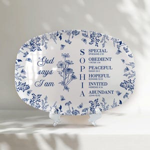 May include: White oval serving platter with a blue floral and butterfly design. The platter has the name "SOPHIA" spelled out vertically with descriptive words and Bible verses. The words "God says I am" are also printed on the platter.
