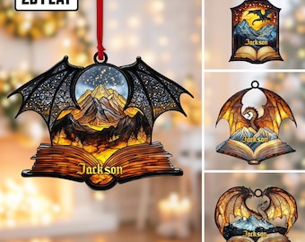 May include: A collection of 2D flat dragon-themed ornaments. Each ornament features a dragon, mountains, and an open book design. The ornaments are in various shapes and colors, with the name "Jackson" displayed on the book.