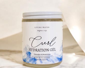 May include: A clear glass jar with a white screw-top lid containing hair product. The label reads Living Water Organics Curl Hydration Gel, Detangles & Moisturizes, Made with Natural Ingredients, featuring a blue watercolor wave design.