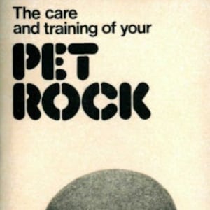 May include: The cover of a book titled "The care and training of your PET ROCK" with a black and white illustration of a large, round, gray rock.