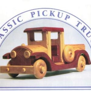 Puede incluir: Un camión de juguete de madera en tonos marrones y rojos. El camión tiene un diseño clásico con ruedas redondas, una llanta de repuesto y las palabras "CLASSIC PICKUP TRUCK" en un arco azul encima. El juguete es de madera.