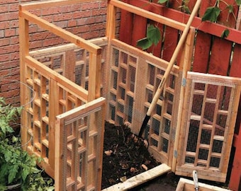 May include: A wooden compost bin with a wire mesh front and a hinged door. The bin is filled with compost and has a shovel leaning against it. There is a small wooden sifter in the foreground.