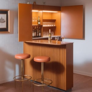 May include: A wooden bar with a built-in cabinet, featuring shelves for glasses and bottles. The bar has a light wood finish and a curved countertop. Two orange bar stools with gold metal bases are positioned in front of the bar.