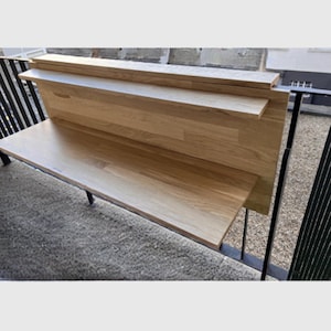 Puede incluir: Una mesa plegable de madera con un estante fijado a la pared. La mesa está hecha de madera clara y tiene un acabado natural. El estante también está hecho de madera clara y tiene un acabado natural.