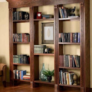 May include: A dark wood bookcase with multiple shelves filled with books. The bookcase has a decorative trim around the top and sides. There are a few decorative items on the shelves, including a vase, a picture frame, and a small sculpture.