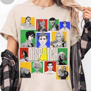 May include: A sand-colored short-sleeve t-shirt featuring a graphic print with the word DISPATCH in large white letters. The design includes a grid of twelve colorful square panels, each displaying a unique illustrated character portrait.