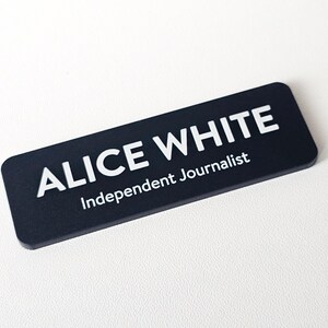 May include: Black name badge with white text that reads "Alice White, Independent Journalist".