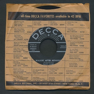 May include: A vintage record sleeve for a 45 RPM record, featuring a black and white label with the text "WALKIN' AFTER MIDNIGHT" by Patsy Cline. The sleeve lists various Decca favorites.