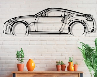 May include: A black metal wire sculpture of a car on a white brick wall. The sculpture is hanging on the wall. There are potted plants on a wooden shelf below the sculpture.