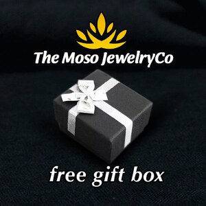 May include: A black gift box with a white ribbon and bow. The box is on a black background. The text "The Moso JewelryCo" is above the box. The text "free gift box" is below the box.