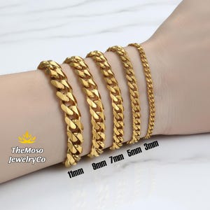 May include: A display of gold-colored curb chain bracelets in various widths: 11mm, 9mm, 7mm, 5mm, and 3mm. The bracelets are shown on a wrist, showcasing the different sizes and styles of the jewelry.