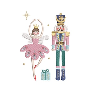 May include: An embroidered design featuring a ballerina fairy in a pink dress with wings, a nutcracker soldier in a pink uniform, and a small gift box. The design includes gold accents and is set against a white background.