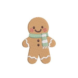 Può includere: Un disegno ricamato di un omino di pan di zenzero. L'omino di pan di zenzero è marrone chiaro con una sciarpa a righe verdi e bianche, guance rosee e un viso sorridente. Il disegno è su sfondo bianco.