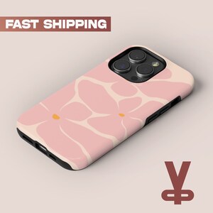 Può includere: Una custodia per telefono rosa con un design floreale. La custodia ha un rigonfiamento della fotocamera nero con tre obiettivi.