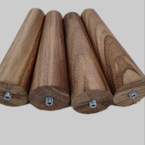 May include: Four wooden furniture legs with a dark brown wood grain finish. Each leg has a metal screw at the bottom.