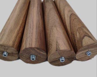 Puede incluir: Cuatro patas de mueble cilíndricas fabricadas en madera natural con un patrón de veta visible. Cada pata presenta un diseño cónico e incluye un perno roscado de metal centrado en la base para su fijación, mostrando la textura de la madera.