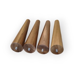 May include: Four wooden furniture legs with a conical design. The legs are made of a light brown wood and have a threaded insert at the base for easy attachment. Each leg is approximately 6 inches tall.
