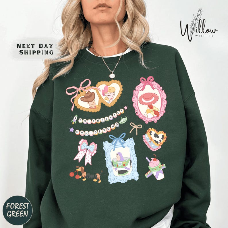 A woman wearing a green sweatshirt with various colorful and whimsical illustrations, including hearts, bows, and other decorative elements.
