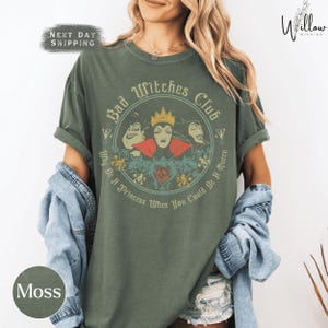 A woman wearing a green t-shirt with a graphic design featuring characters from the Disney film "Bad Witches".