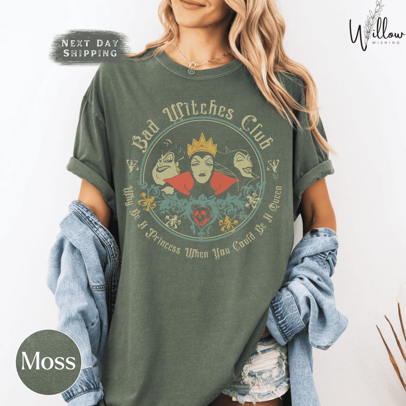 A woman wearing a green t-shirt with a graphic design featuring characters from the Disney film "Bad Witches".