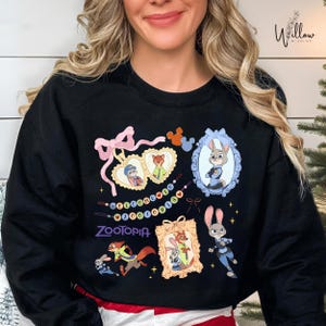 A woman wearing a black sweatshirt with various cartoon animal characters and a pink bow on it.