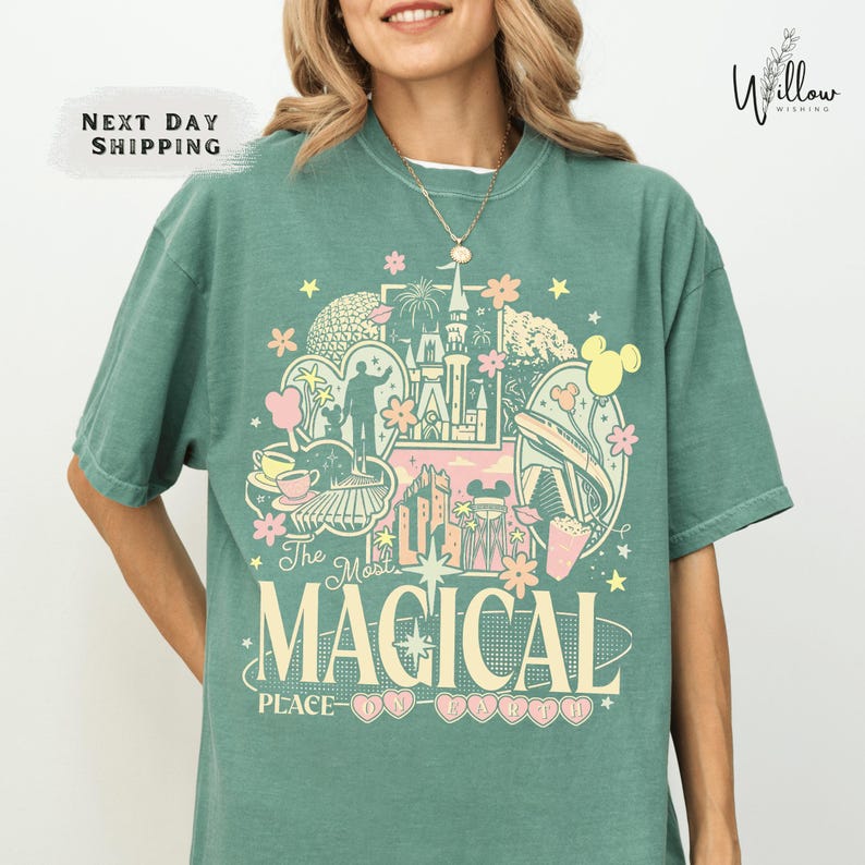 A woman wearing a green t-shirt with a colorful graphic design featuring various Disney-themed elements such as Mickey Mouse, Minnie Mouse, and a castle.