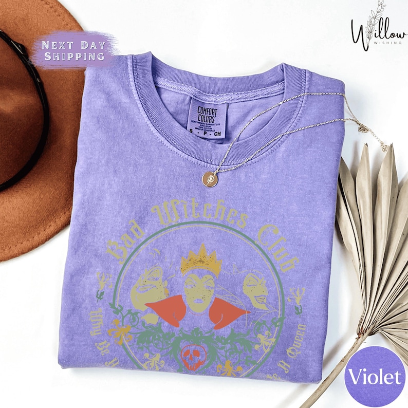 a purple t-shirt with a graphic design, a brown hat, and a fan, all placed on a white background.