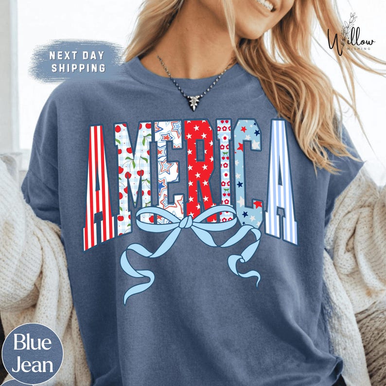 A woman wearing a blue t-shirt with the word "AMERICA" printed on it, along with a bow and ribbon design.