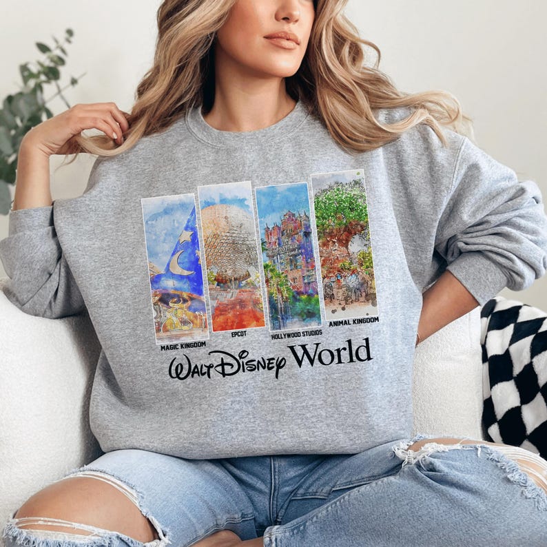 A woman wearing a gray sweatshirt with a graphic design featuring various Disney landmarks and the text "Walt Disney World".