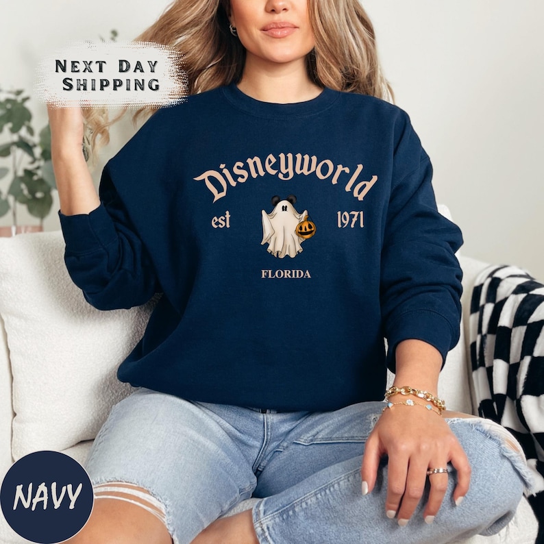 a woman sitting on a couch wearing a disneyland world sweatshirt