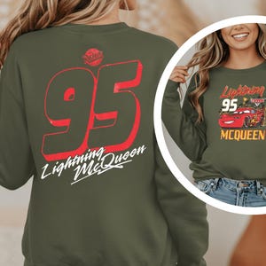 A woman wearing a green sweatshirt with a red and white design on the back, featuring the number 95 and the text "Lightning McQueen".