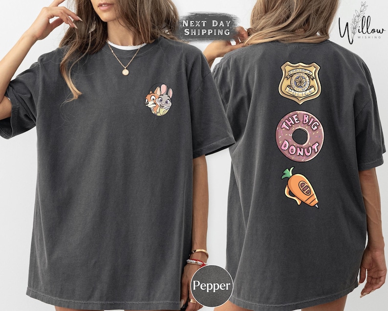 A woman wearing a gray t-shirt with various cartoon characters and designs, including a police badge, a donut, and a carrot.