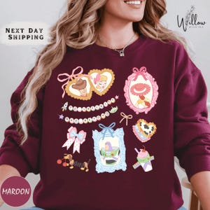 A woman wearing a burgundy sweater with various cartoon-style illustrations and text on it.